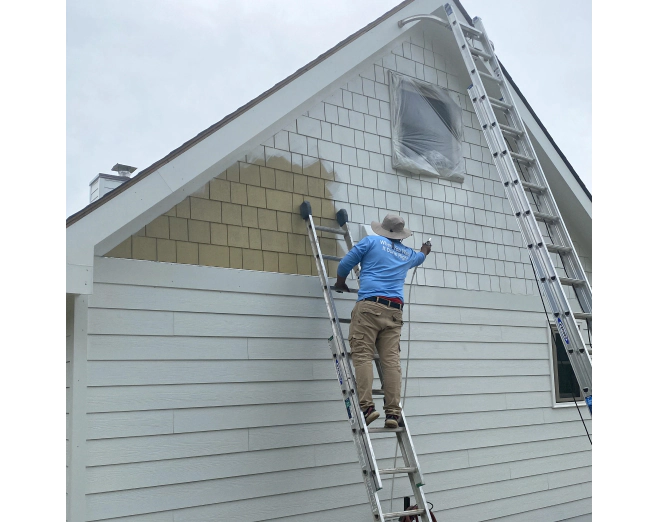 man painting siding of house